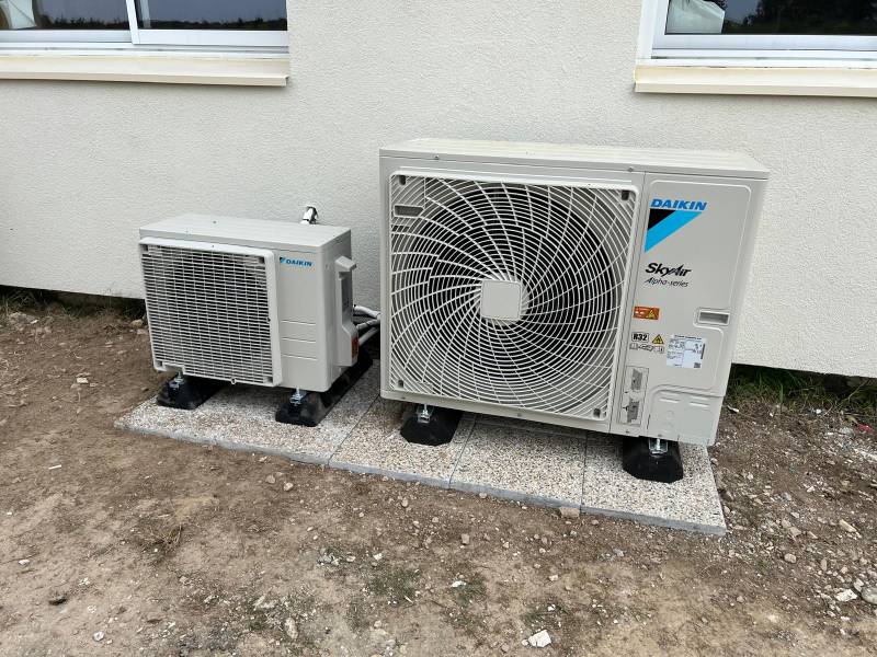  Deux unités extérieures Daikin de tailles différentes posées sur plots antivibratiles le long de la façade d'un bâtiment neuf à Montpellier et Lattes